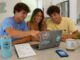 Student group planning a beach house rental booking together at a laptop — North Myrtle Beach group trip
